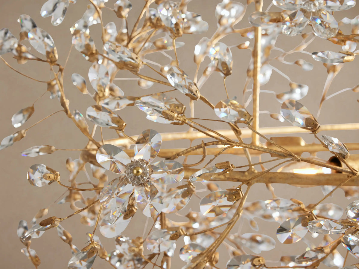 Close-up of Fiore Crown Chandelier featuring intricate golden branches with clear faceted crystal leaves and flowers, showing an antique finish.