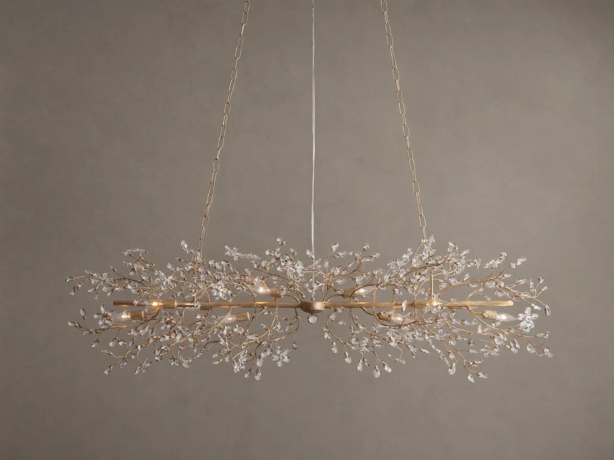Fiore Linear Chandelier, golden finish, adorned with delicate branching crystal leaves, exposed candelabra bulbs, suspended by chains.