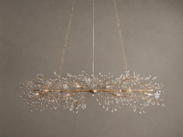 Fiore Linear Chandelier, golden finish, adorned with delicate branching crystal leaves, exposed candelabra bulbs, suspended by chains.