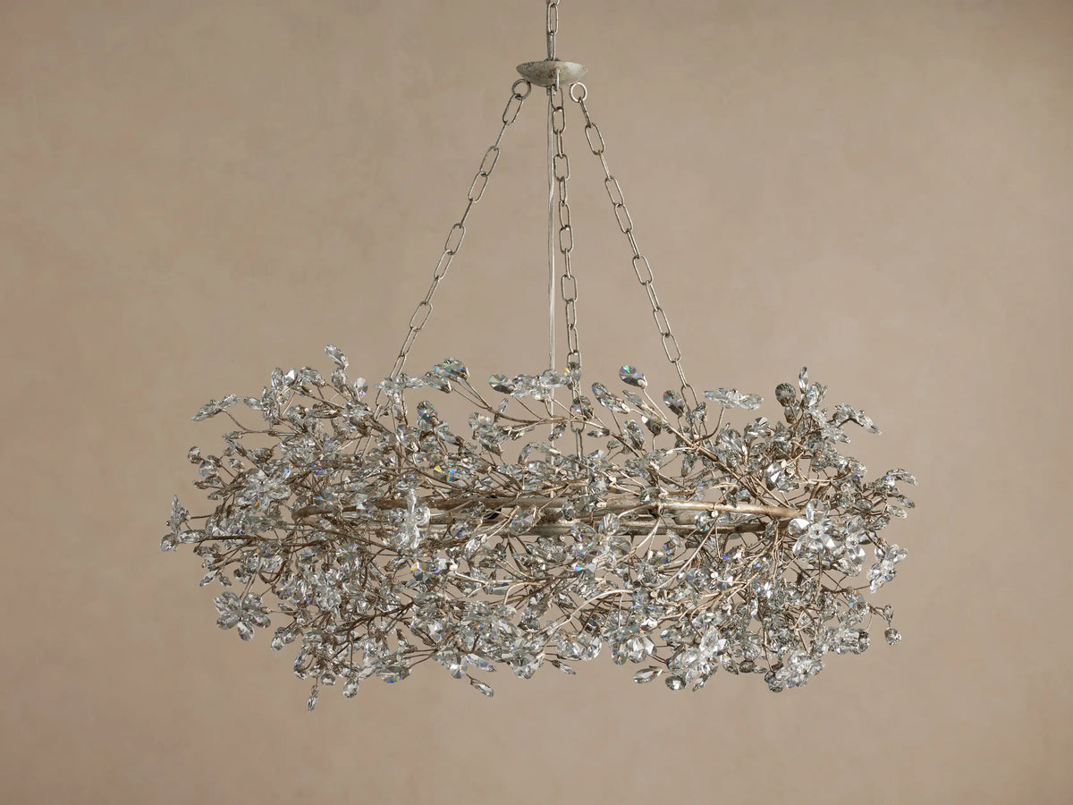 Fiore Crown Chandelier, oval silver-tone fixture adorned with many clear crystal leaves, suspended by metal chains.