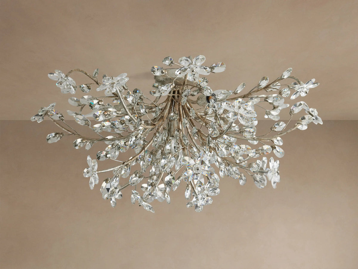 Fiore Flush Mount: ornate ceiling fixture with antiqued gold-toned branches, adorned with clear crystal flowers and leaves, illuminated.