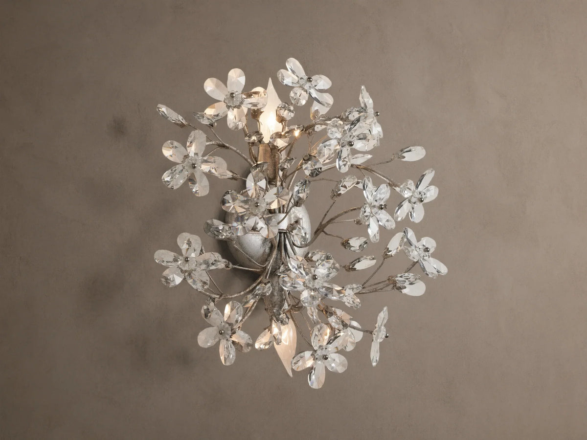 Antiqued silver Fiore Sconce, wall-mounted, featuring numerous clear crystal flowers & buds, with two lit candelabra bulbs.