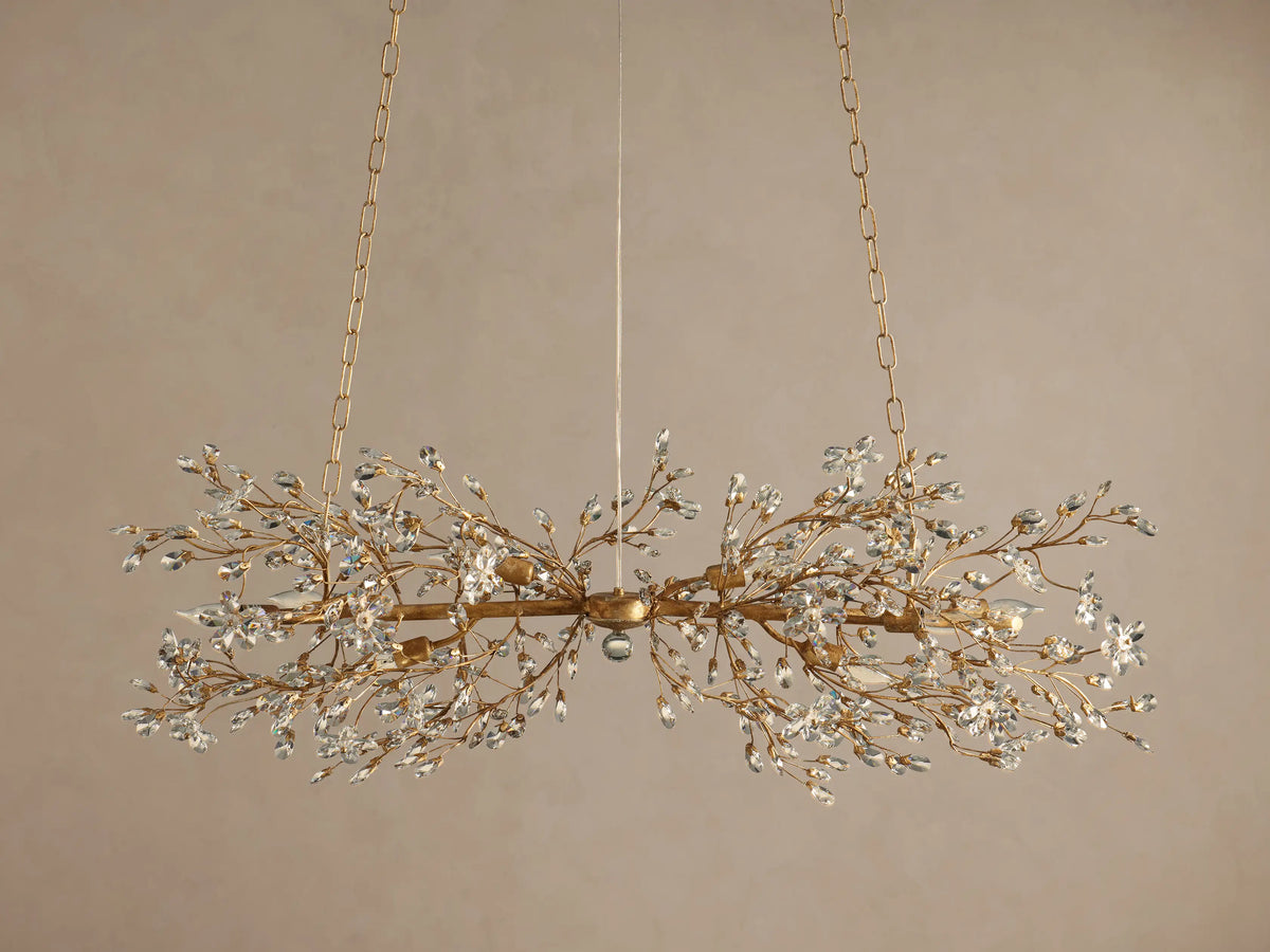 Gold Fiore Linear Chandelier suspended by chains, featuring delicate branches adorned with numerous clear crystal leaves & flowers.