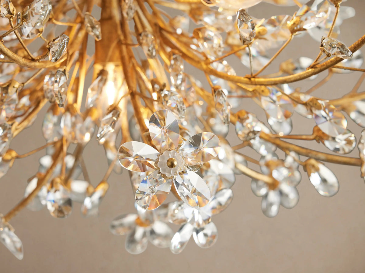 Fiore Flush Mount. Ornate antique gold fixture with branching arms & sparkling clear crystal flowers, mounted on a ceiling.