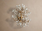 Fiore Sconce: Elegant gold iron sconce with clear crystal flowers, sparkling and glowing with warm light, mounted on a neutral wall.