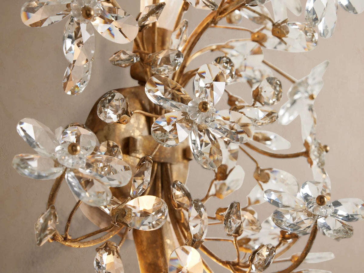 Fiore Sconce: An antiqued gold wall fixture, a bouquet of clear crystal flowers and leaves, mounted on a light beige wall.