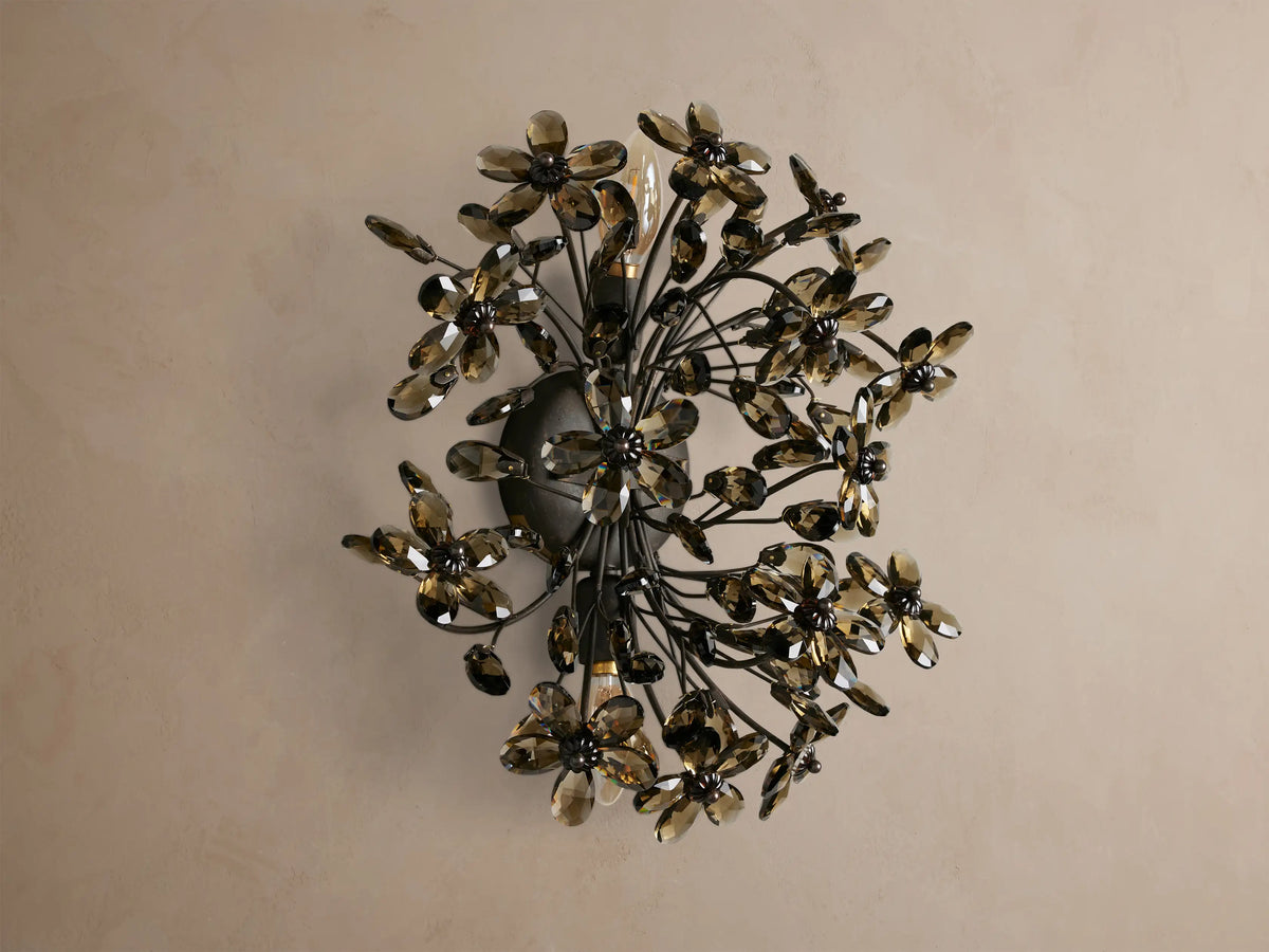 Fiore Sconce: Wall-mounted light with dark metal branches holding numerous smoky brown crystal flowers, radiating warm light.