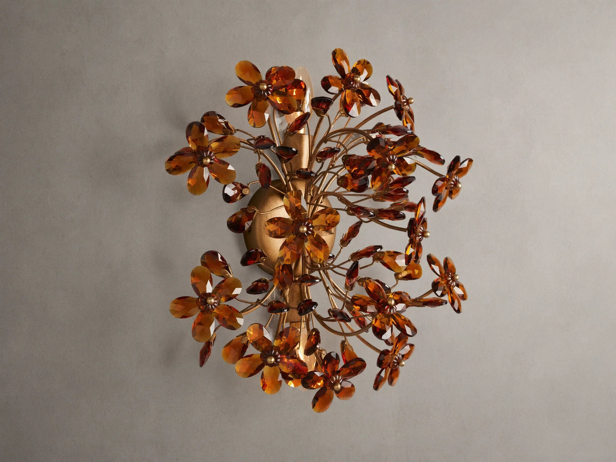 Fiore Sconce with a gold antiqued leaf design, featuring amber-colored flower-like structures radiating outward from a central base.