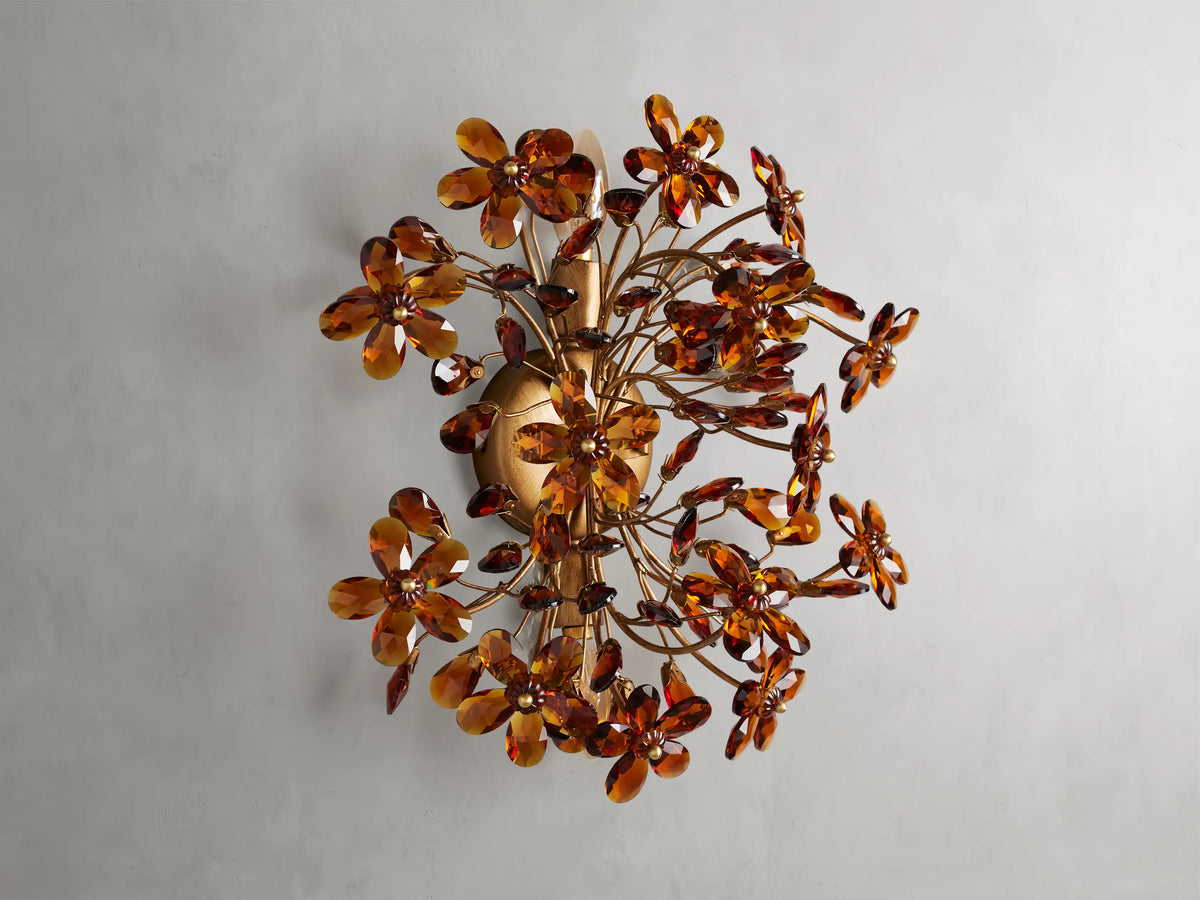 Fiore Sconce with a gold antiqued leaf design, featuring amber-colored flower-like structures radiating outward from a central base.
