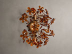 Fiore Sconce with a gold antiqued leaf design, featuring amber-colored flower-like structures radiating outward from a central base.