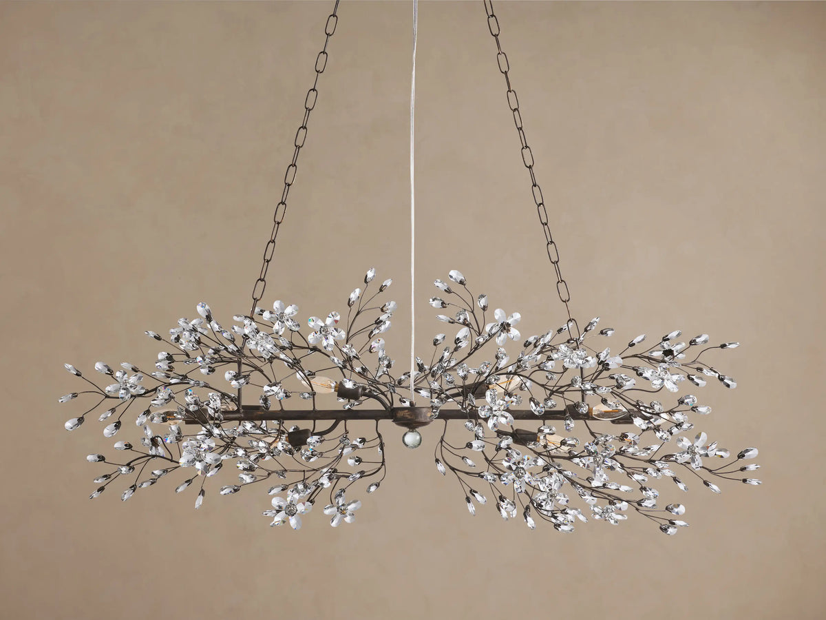 Fiore Linear Chandelier, dark iron frame with clear crystal flowers & buds, linear shape, warm glowing bulbs.