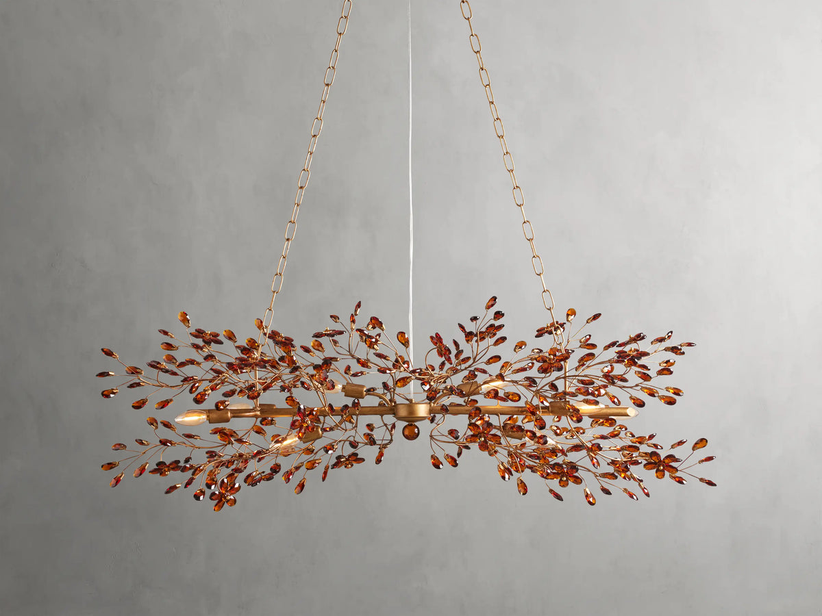 Fiore Linear Chandelier with bronze finish and ornate branching leaf design, suspended by chains against a plain background.