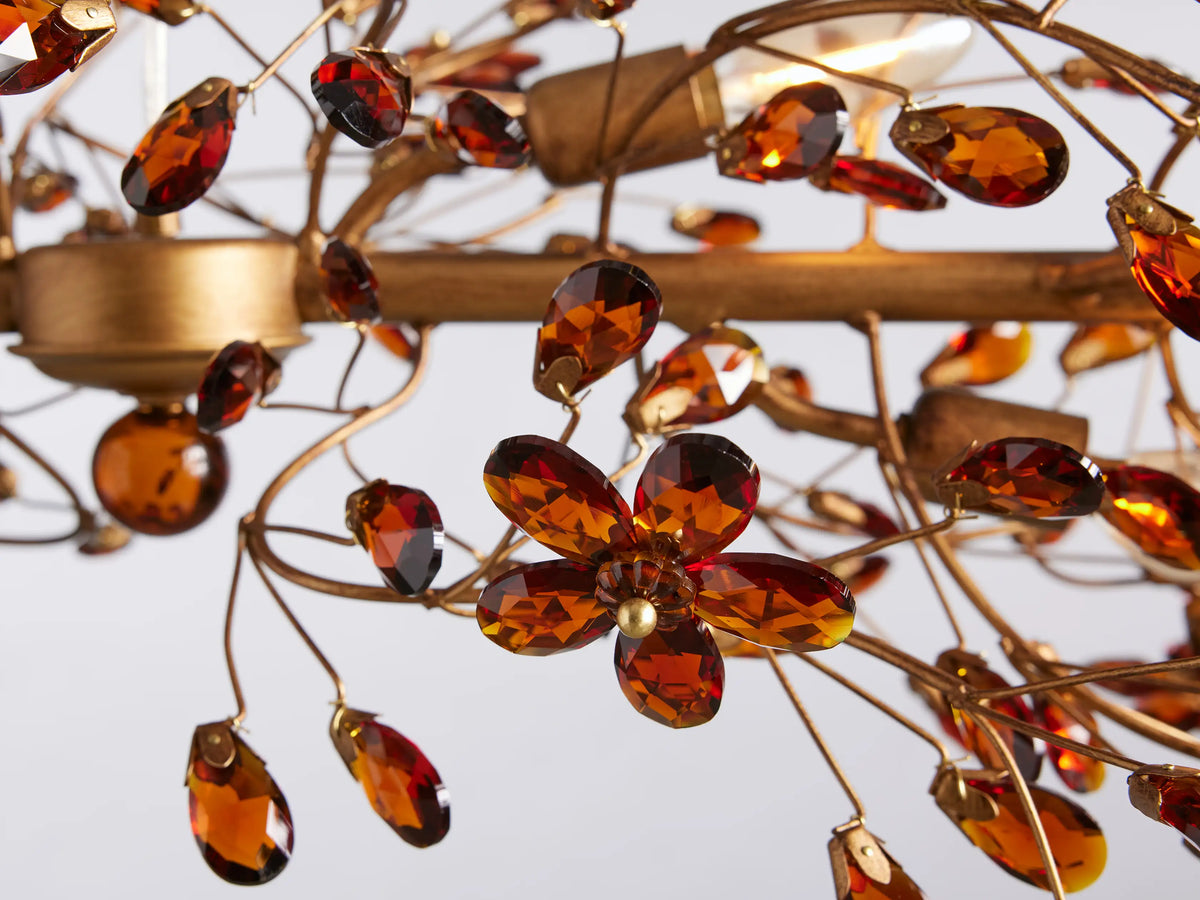 Fiore Linear Chandelier with intricate bronze leaf design, suspended by two gold chains and a central clear cord against a neutral background.