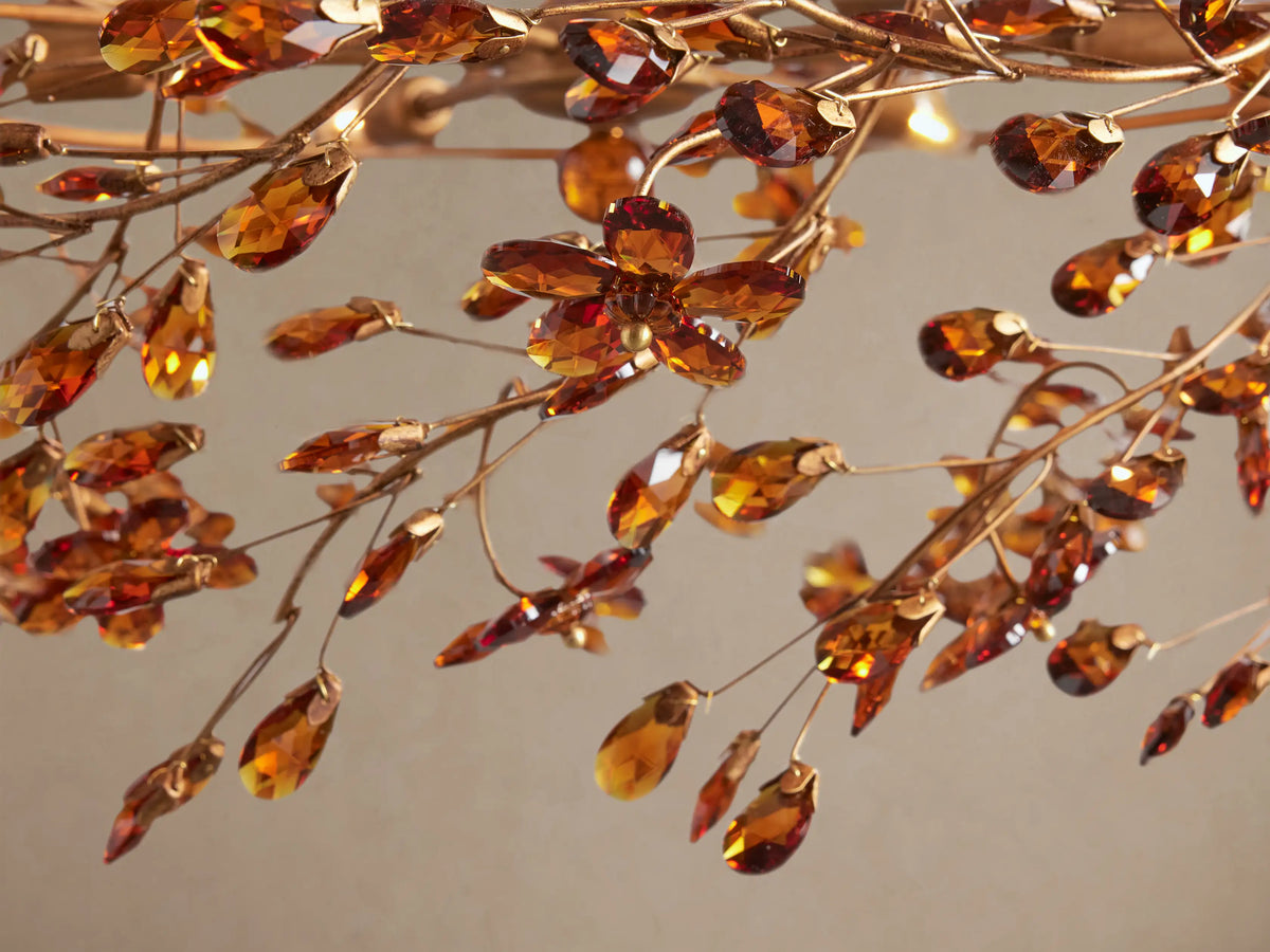Fiore Crown Chandelier: Golden circular chandelier adorned with numerous sparkling amber leaf-shaped pieces, hanging from golden chains.