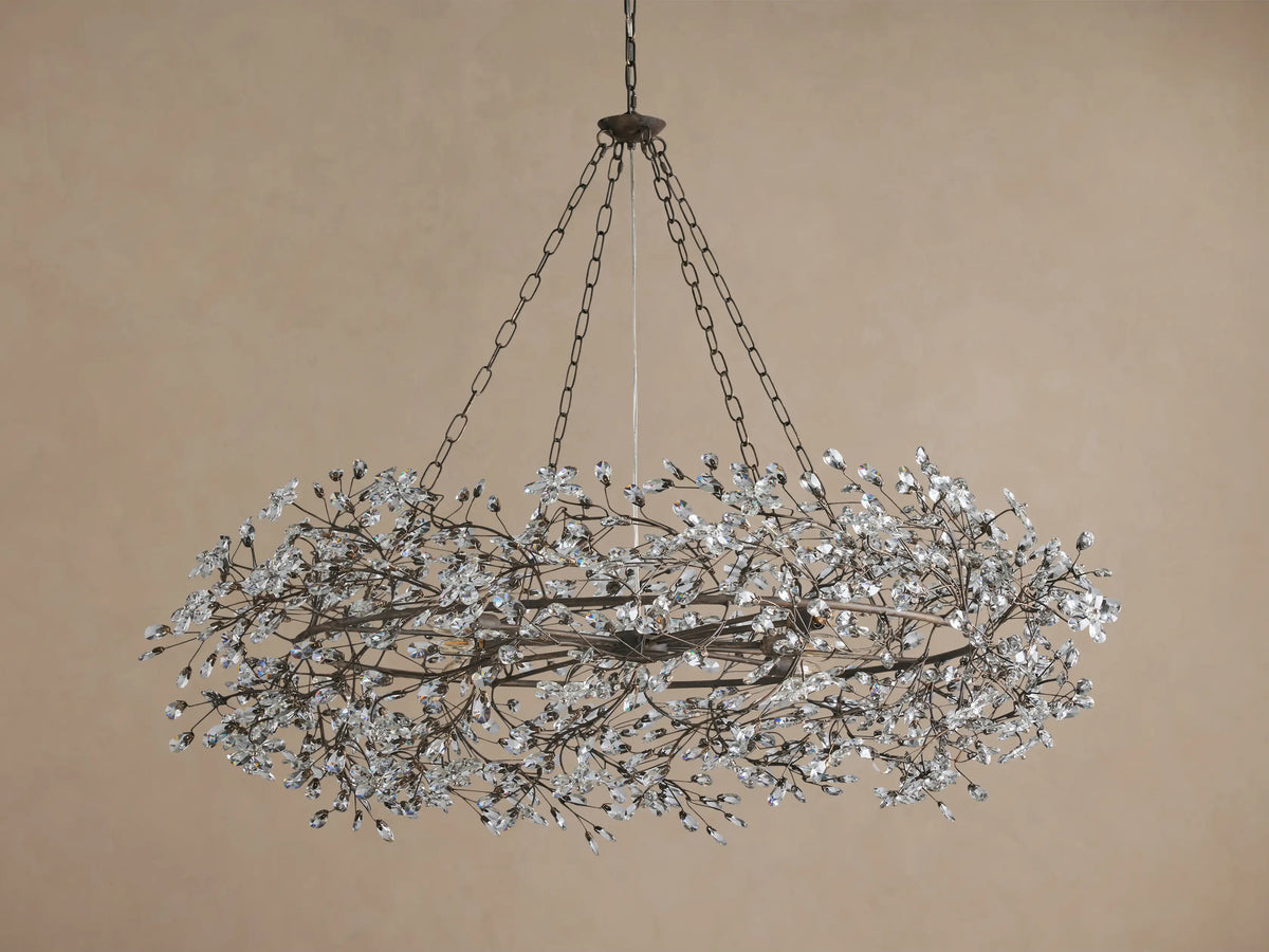 Fiore Crown Chandelier: oval iron frame in antiqued bronze, adorned with numerous clear crystal floral pieces, suspended by chains.