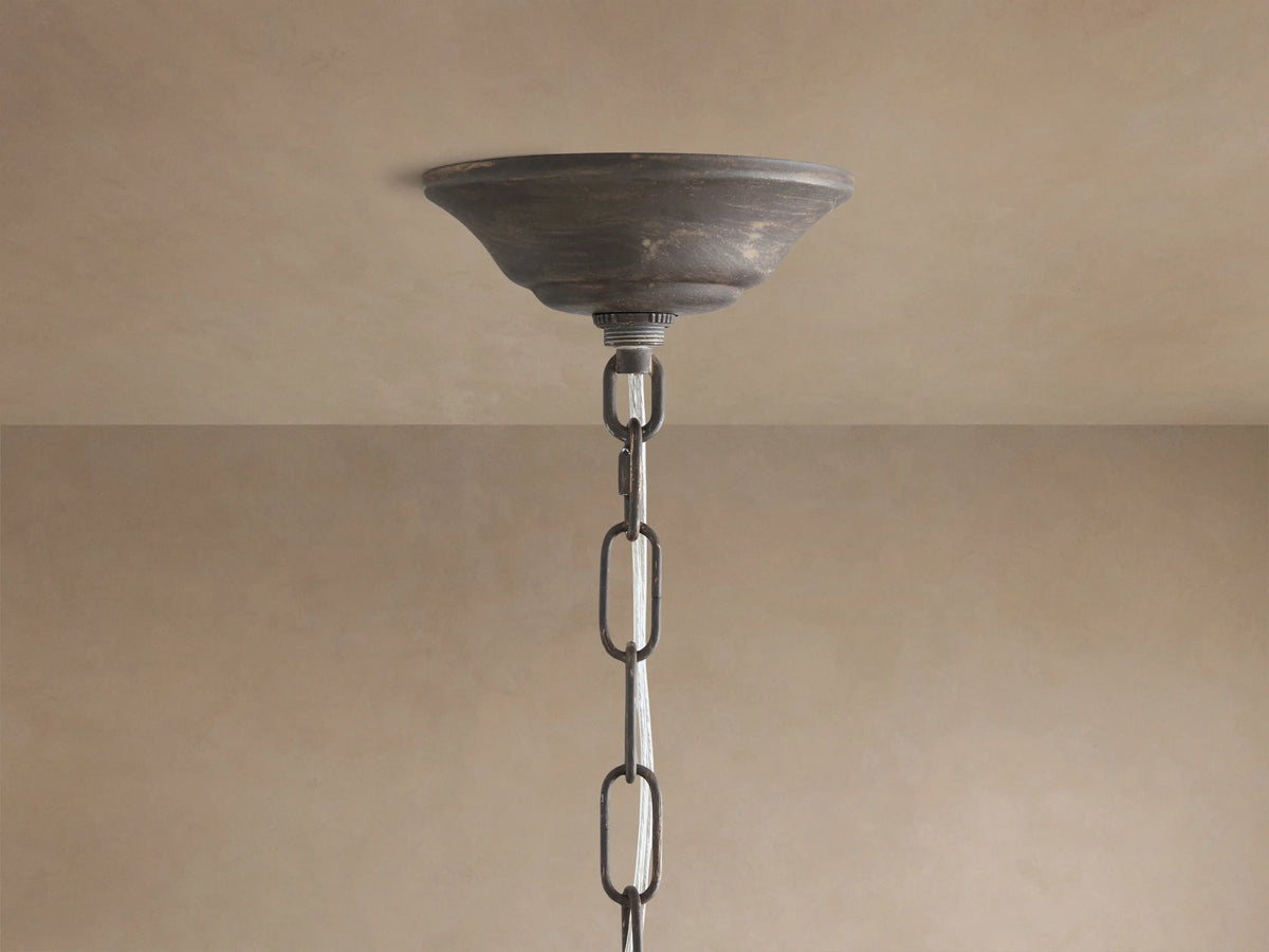 Fiore Crown Chandelier: Distressed bronze ceiling canopy and thick chain hanging from a light beige ceiling.