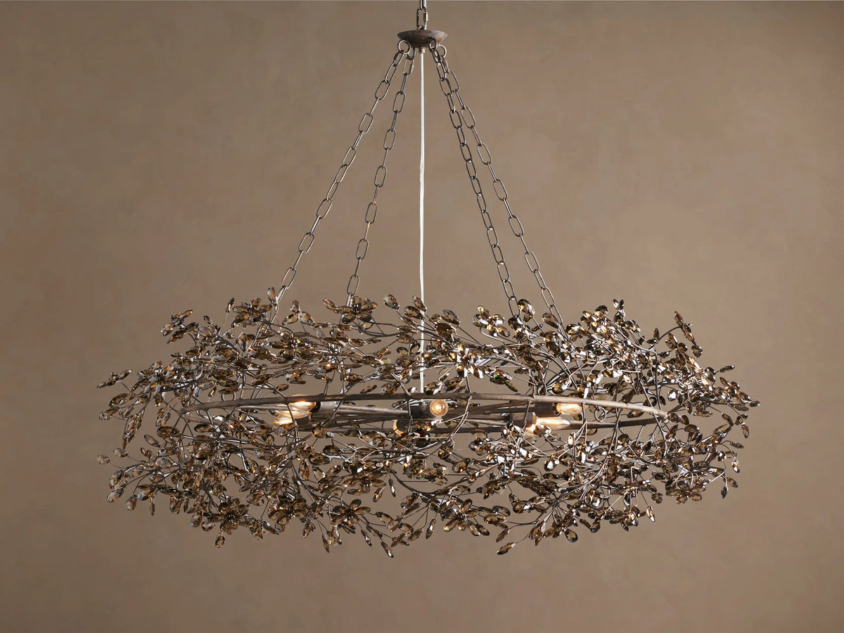 Fiore Crown Chandelier, an antique metal wreath-shaped fixture with many amber leaf-like crystals, hanging from chains.