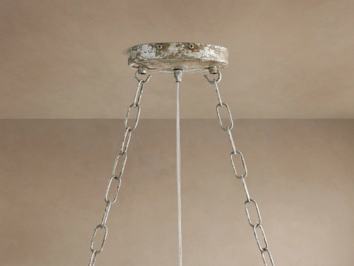 Fiore Crown Chandelier's distressed silver ceiling canopy & three chains hang from a light beige ceiling.