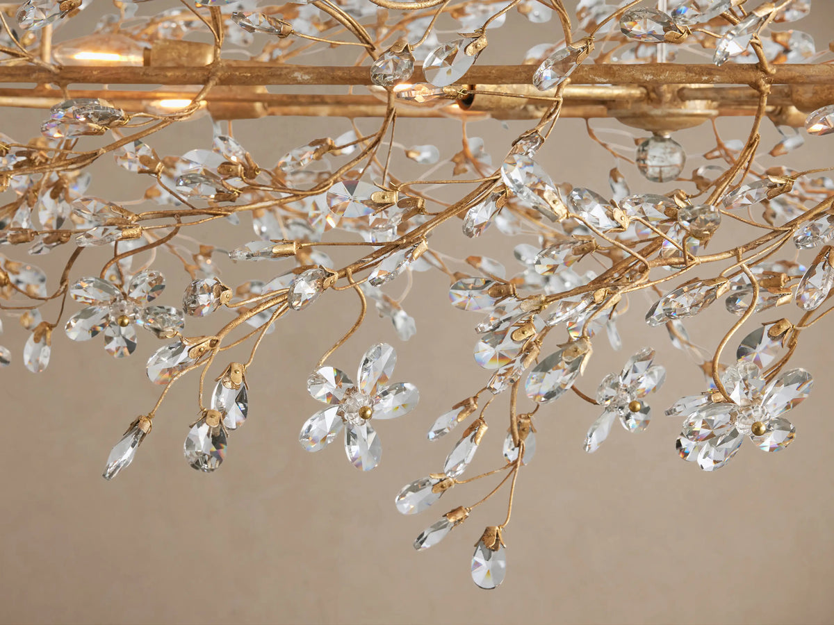 Fiore Oval Chandelier, gold metal frame with intricate branches covered in sparkling clear crystal leaves, hanging from gold chains.