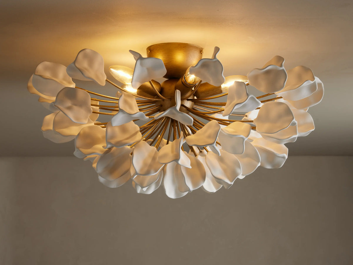 Lunaria Flush Mount with cascading white ceramic leaves and a brass base, lit softly from above, mounted on a ceiling.