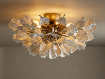 Lunaria Flush Mount with cascading white ceramic leaves and a brass base, lit softly from above, mounted on a ceiling.