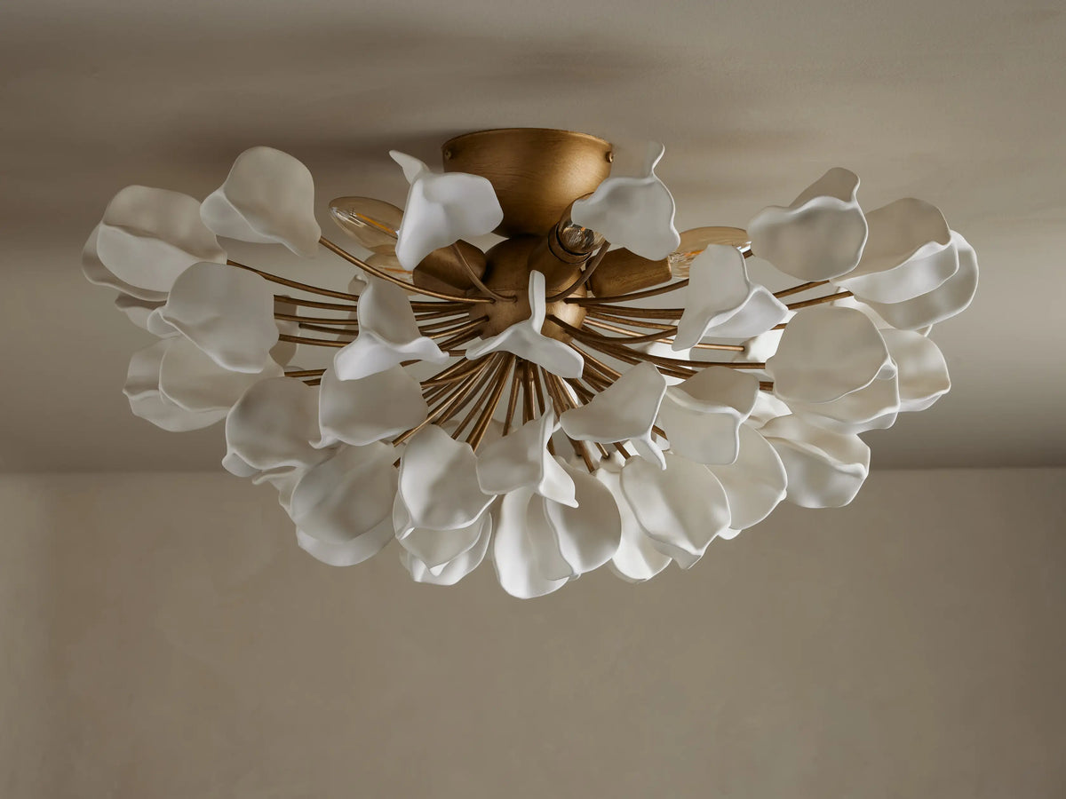 Lunaria Flush Mount with cascading white ceramic leaves and a brass base, lit softly from above, mounted on a ceiling.