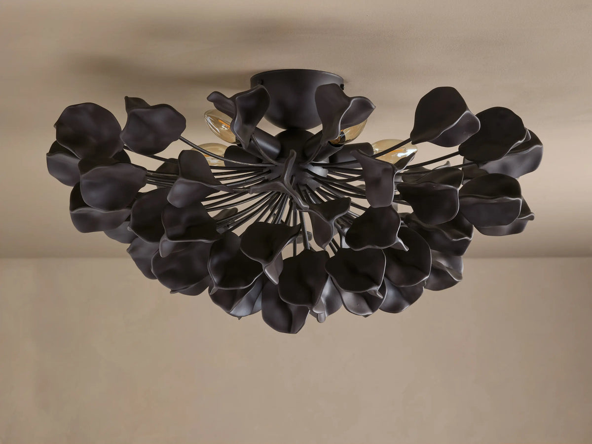 Lunaria Flush Mount with dark iron finish and ceramic leaves, illuminated from behind, mounted on beige ceiling.