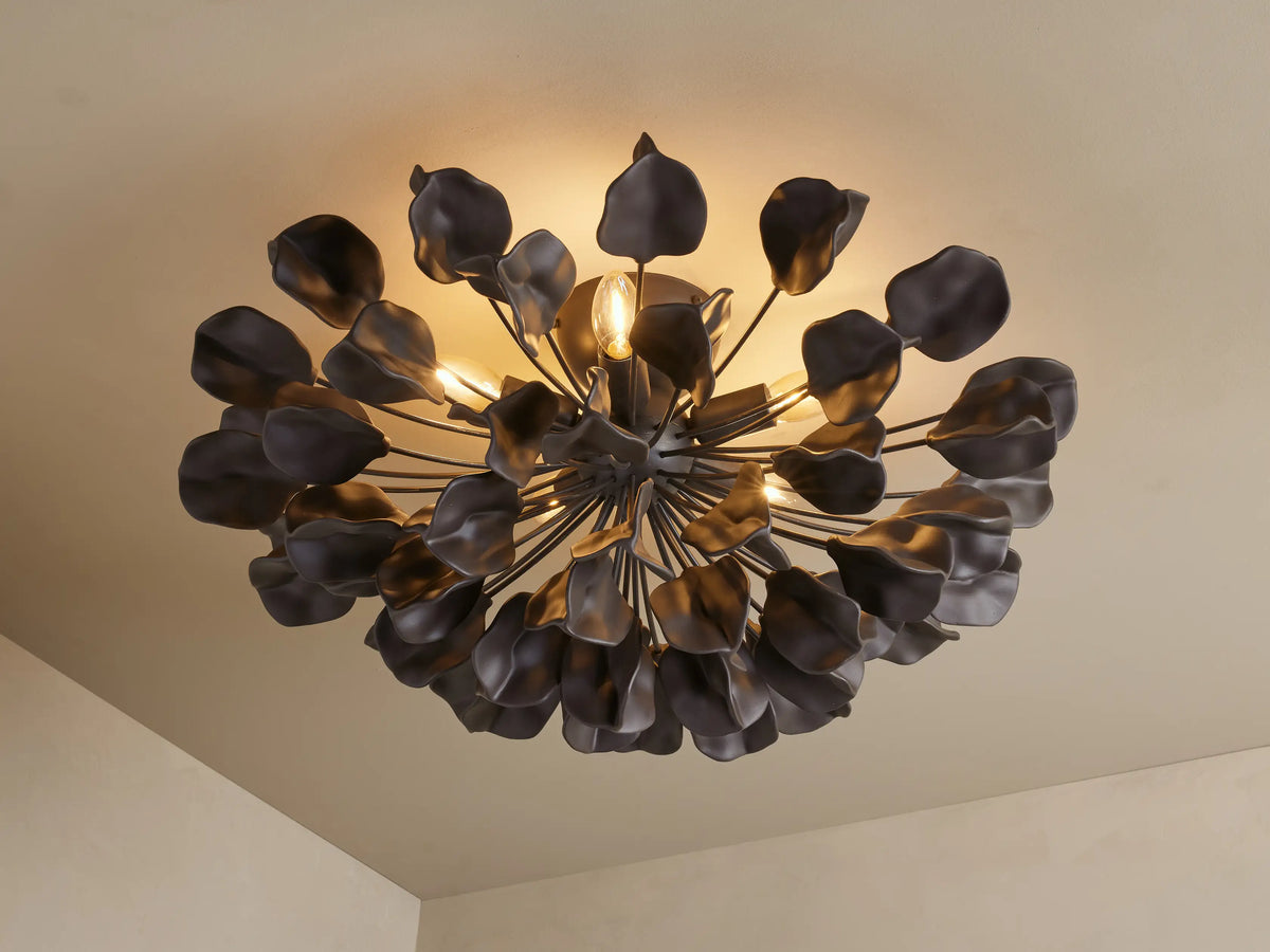 Lunaria Flush Mount with black iron and ceramic leaves, radiating from the center. Warm lighting illuminates textured leaves.