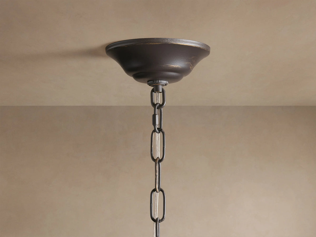 Alt text: Close-up of the Lunaria Chandelier showing intricate ceramic leaves with a smooth texture, mounted on thin iron stems. The leaves are artistically arranged, creating an elegant and decorative pattern with a warm light glow in the background.