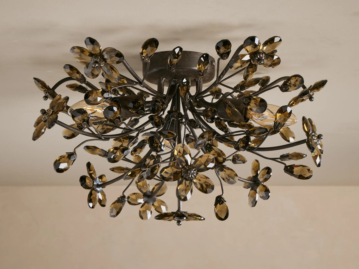 Ornate Fiore Flush Mount light, dark metal branches adorned with smoky crystal flowers and warm glowing bulbs, mounted on ceiling.