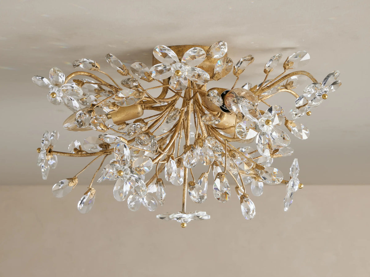 Fiore Flush Mount, an elegant gold light fixture with numerous clear crystal flower and teardrop shapes sparkling on a ceiling.