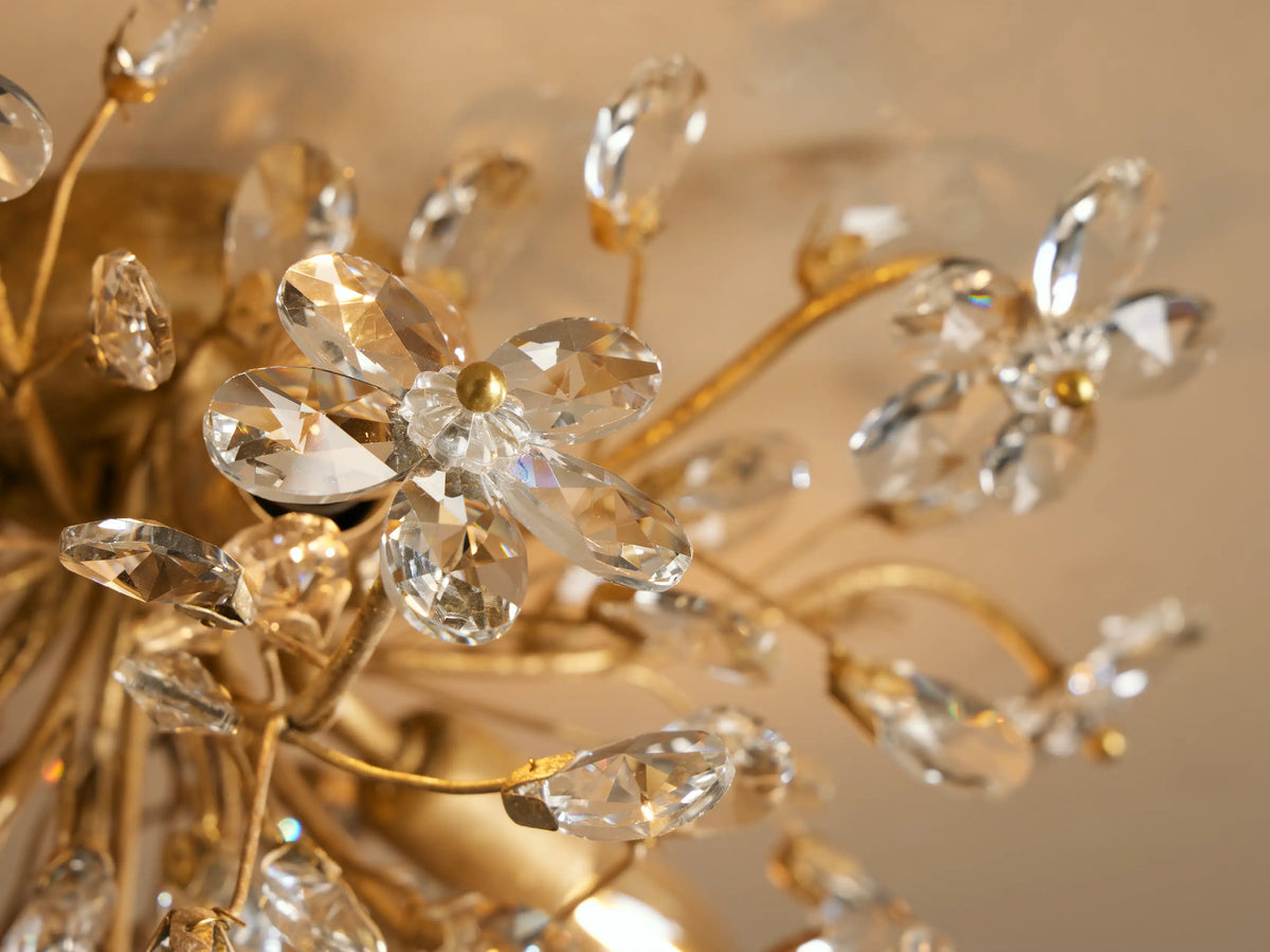 Fiore Flush Mount: Gold-toned flush mount light with numerous clear crystal flowers and teardrop shapes, mounted on a ceiling.