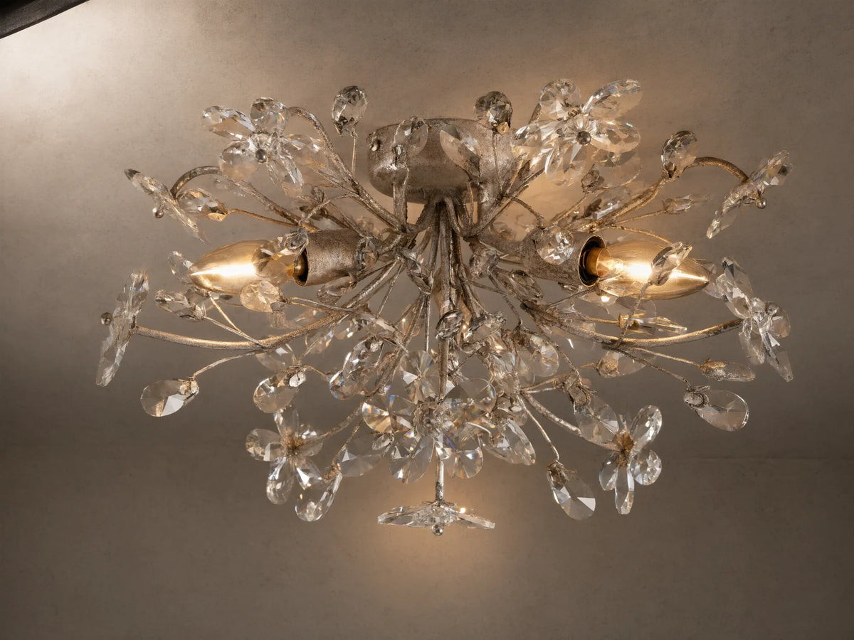 Fiore Flush Mount light fixture with intricate antique silver floral branches adorned with clear crystal flowers and leaves, illuminated.