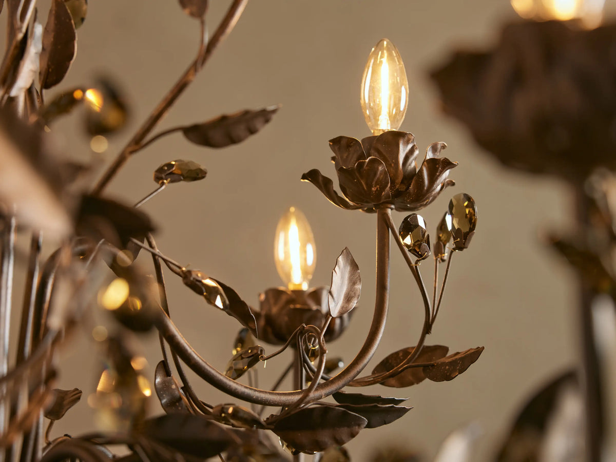Nicoletta Round Chandelier with dark bronze finish, intricate leaves, illuminated candle-style bulbs, and smoke crystals.