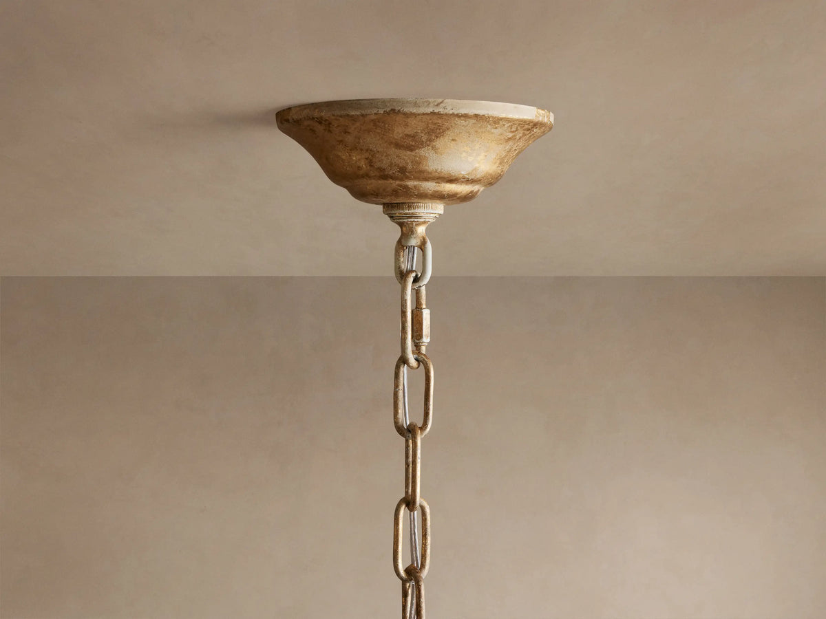Close-up of Nicoletta Round Chandelier, golden leaf-like metalwork with clear crystal accents, and warm glowing light bulbs.