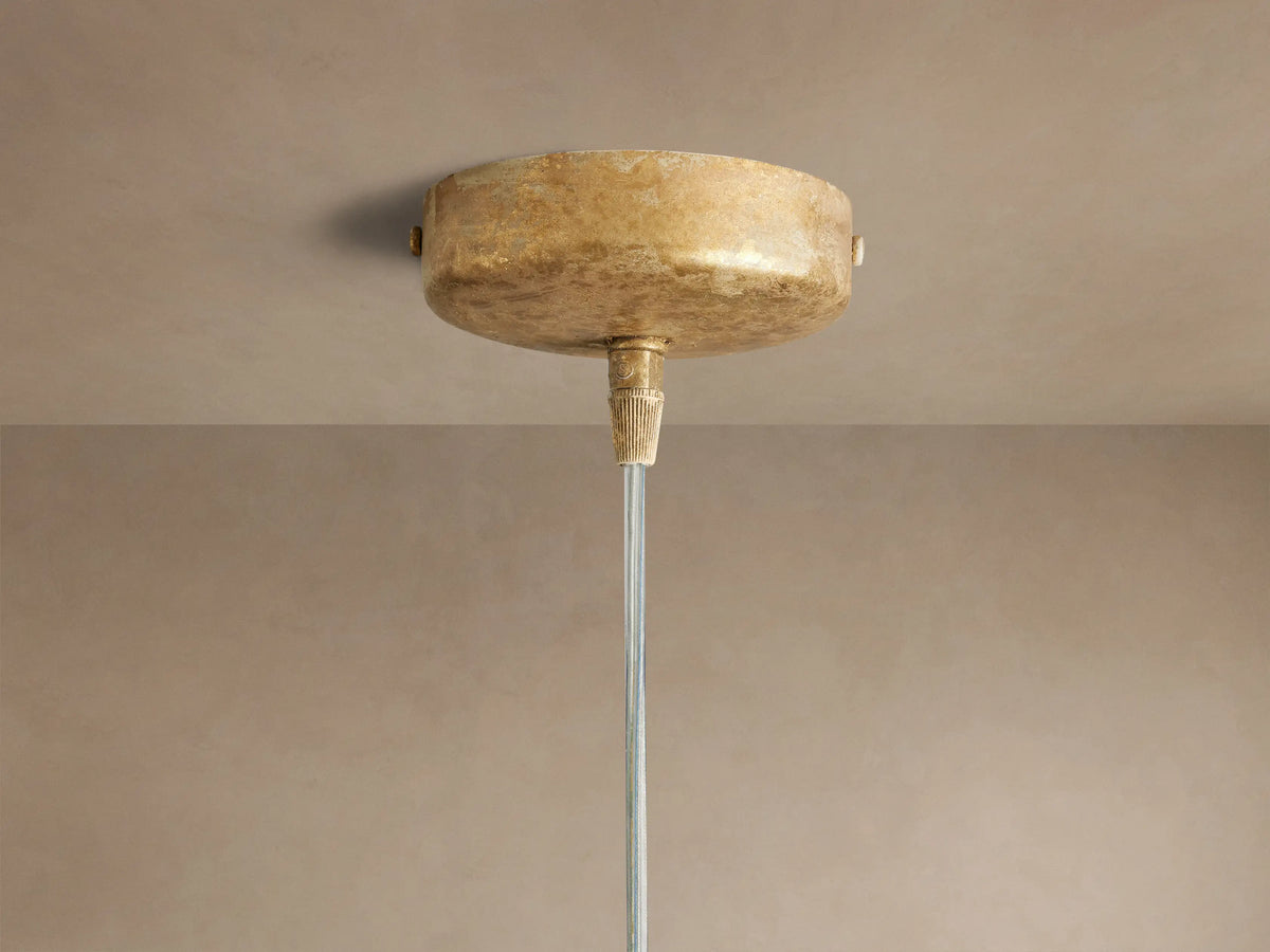 Close-up of the Lorca Pendant, with overlapping, textured gold/bronze petal-like layers & a warm glowing bulb.