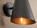 Elih Sconce in antiqued bronze finish, a wall-mounted light with a round backplate and downward-angled conical shade.