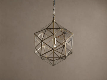 Eliana Lantern Pendant: Geometric brass and clear glass lantern hanging from a black chain, with a light bulb inside.