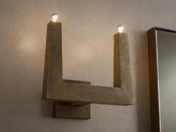 Front view of textured bronze U-shaped wall sconce with two glowing bulbs.