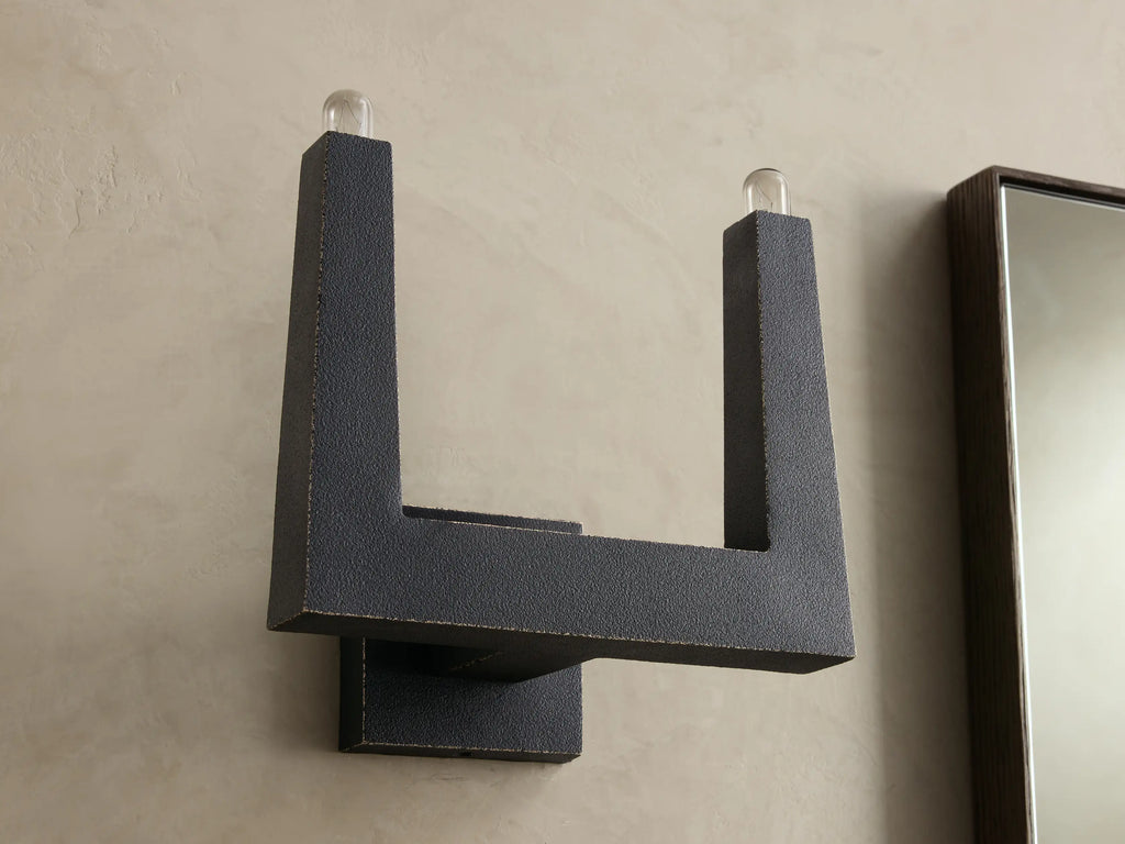 Front view of a dark gray textured U-shaped wall sconce with two clear glass bulbs at the top.