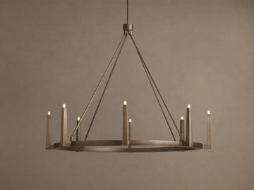 Emmet Round Chandelier in antiqued brass, with 8 illuminated candle-like lights on a circular frame, suspended from above.
