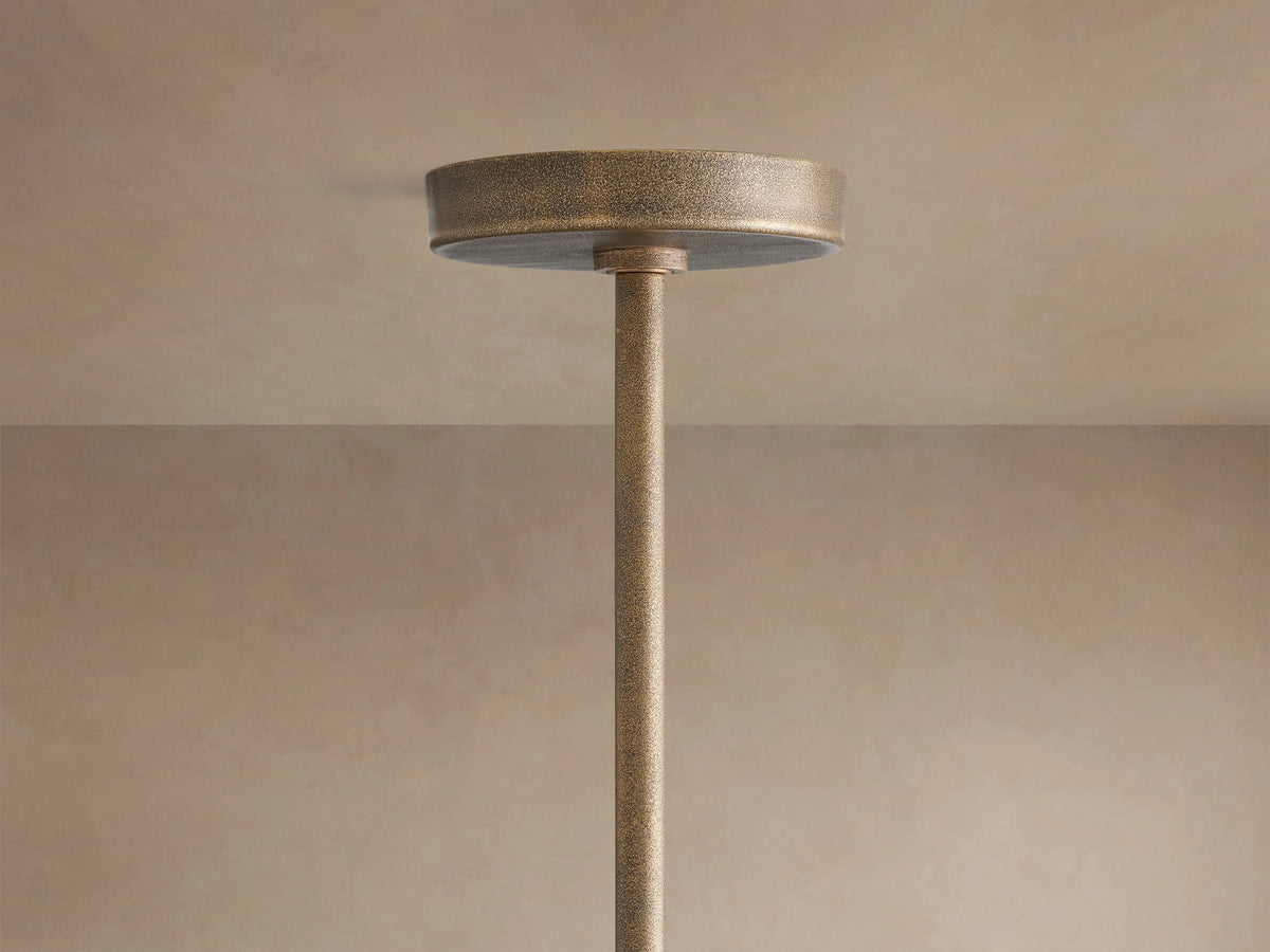 Close-up of Emmet Round Chandelier, showing its textured antiqued brass finish, sturdy round frame, vertical arms with glowing bulbs.
