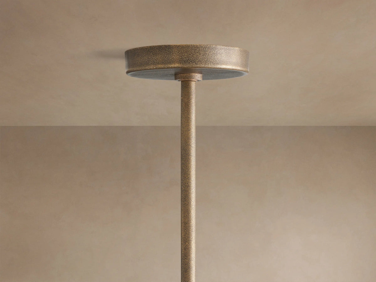 Emmet Round Chandelier, close-up. Textured antiqued brass ring and vertical arms with glowing filament bulbs.