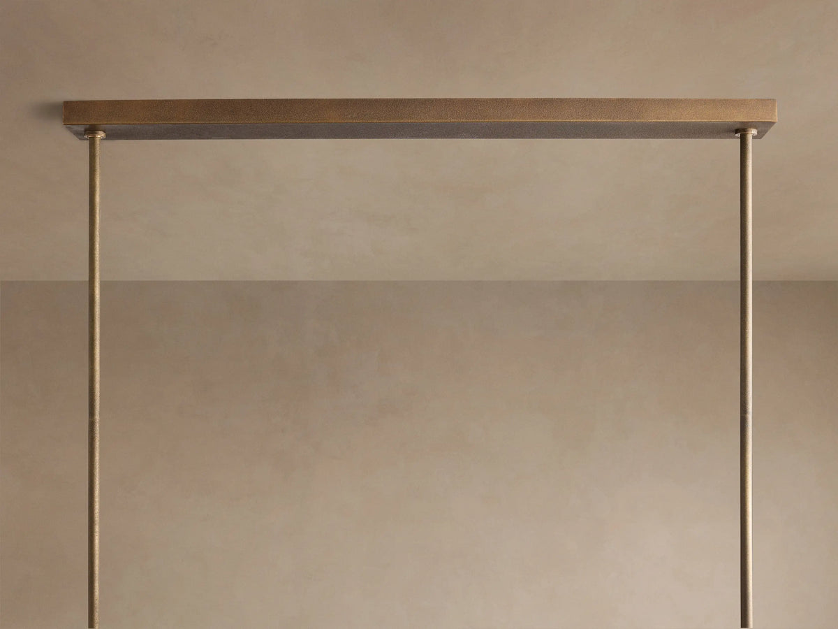 Close-up of Emmet Linear Chandelier in textured antiqued brass with multiple rectangular arms angled upwards, each with a lit bulb.