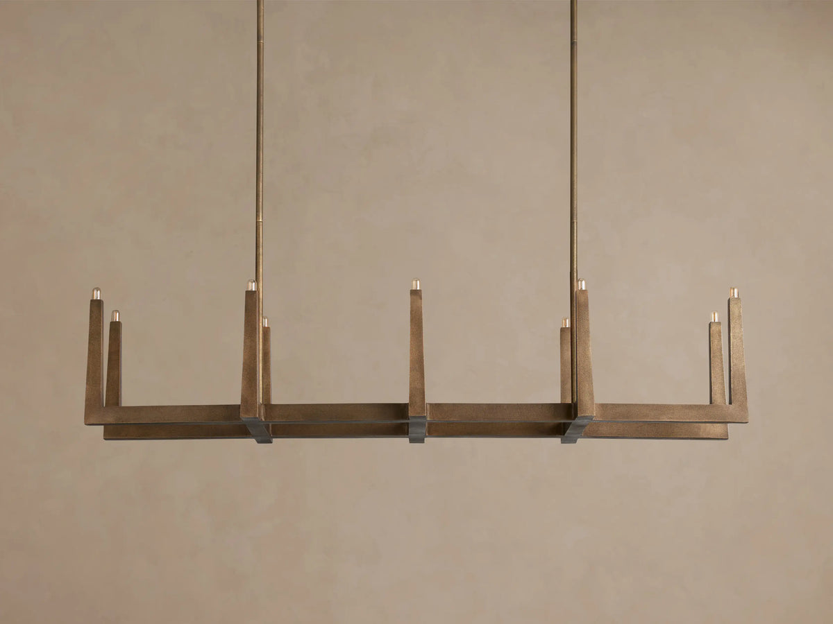 Emmet Linear Chandelier with antiqued brass finish, featuring a rectangular frame and multiple illuminated candle-like bulbs.
