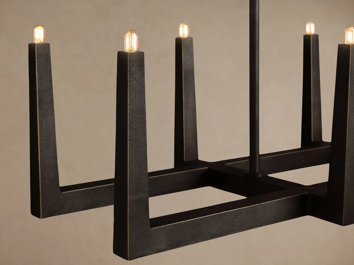Emmet Linear Chandelier, dark antiqued brass, rectangular frame with eight upward-facing candle-style lights, hanging by rods.