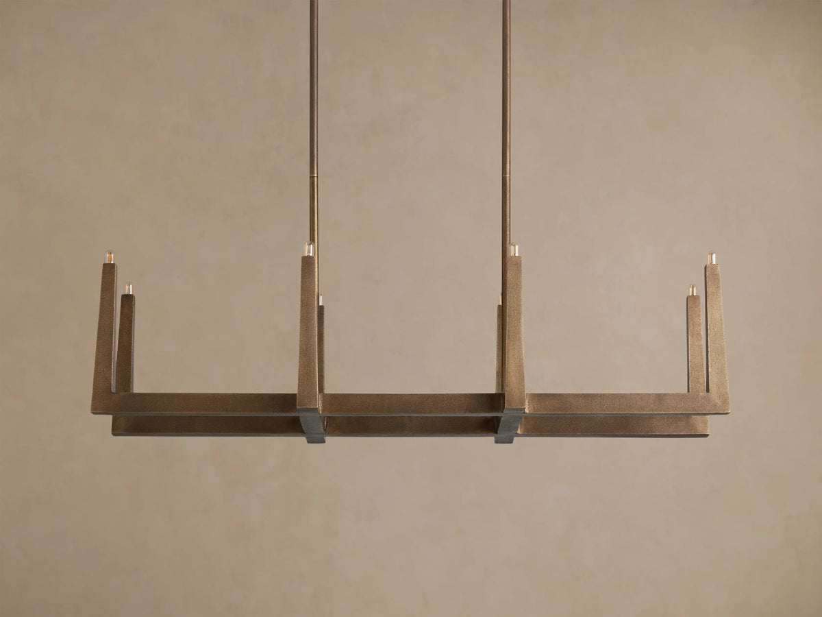 Emmet Linear Chandelier: Textured antiqued brass, linear rectangular frame with illuminated upright bulbs, suspended from rods.