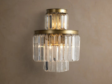 Leyland Sconce: a tiered wall light with illuminated clear K9 glass crystals & an oil-rubbed bronze-toned frame against a wall.