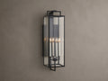 Hendricks Outdoor Sconce: black iron frame with clear glass panels, four lit candle-style bulbs, mounted vertically on a taupe wall.