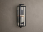 Hendricks Outdoor Sconce: black iron frame with clear glass panels, four lit candle-style bulbs, mounted vertically on a taupe wall.